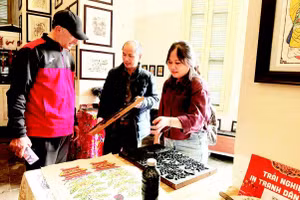 Võ Ca Dao hướng dẫn cho du khách nước ngoài trải nghiệm in tranh mộc bản.