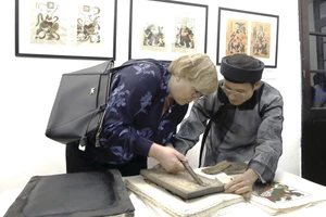 Nghệ nhân Nguyễn Hữu Quả giới thiệu kỹ thuật in tranh Đông Hồ tới du khách quốc tế, tại Bảo tàng Mỹ thuật Việt Nam.