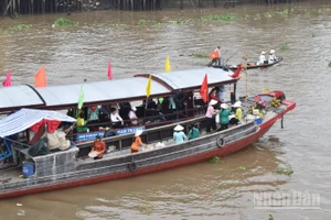 Tái hiện cảnh mua bán giữa thương lái và khách du lịch tại chợ nổi Cái Bè sáng 4/12/2025.