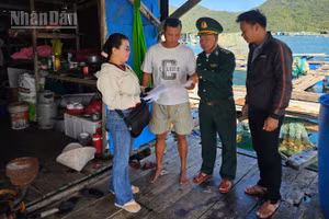 Cán bộ Đồn Biên phòng An Hải cùng các chủ phương tiện và ngư dân trao đổi, hướng dẫn kê khai, rà soát hồ sơ tàu cá tại lồng bè. (Ảnh: THÙY DUNG)