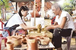 Du khách trải nghiệm làm đồ gốm khi tới thăm làng Thanh Hà.