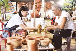 Du khách trải nghiệm làm đồ gốm khi tới thăm làng Thanh Hà.