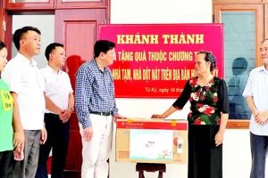 Đại diện chính quyền địa phương tặng quà gia đình bà Phạm Thị Thoa (ở xã Lạc Phượng) được hỗ trợ xây nhà mới.