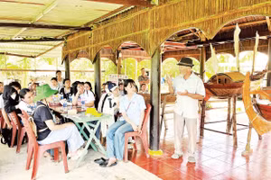 Du khách lắng nghe kể chuyện giữ gìn nghề đóng ghe bầu tại Làng mộc Kim Bồng.