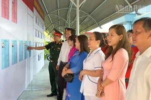 Cán bộ và người dân xem danh sách ứng cử. 