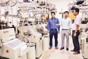 Anh Nguyễn Thanh Bình (đứng giữa), Giám đốc Công ty TNHH Begen, giới thiệu về dây chuyền sản xuất bít-tất xuất khẩu.