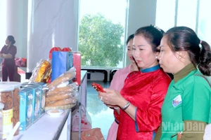 Khách hàng tham quan trưng bày sản phẩm OCOP bên lề hội nghị và trải nghiệm quét mã truy xuất nguồn gốc sản phẩm được in trên bao bì.