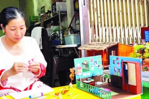 Chị Nguyễn Hồng Phúc cặm cụi từng chi tiết cho những mô hình “nhà xưa” thu nhỏ để lưu giữ ký ức tuổi thơ.