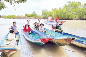 Cán bộ đến tận những căn nhà dân dựng ven sông để trao thẻ cử tri, mang lại niềm vui và sự an tâm cho người dân vùng sâu.