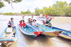 Cán bộ đến tận những căn nhà dân dựng ven sông để trao thẻ cử tri, mang lại niềm vui và sự an tâm cho người dân vùng sâu.