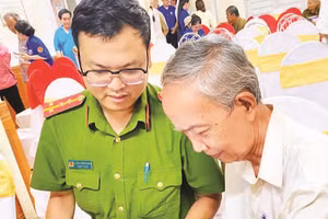 Cán bộ Công an phường Thuận Hóa hỗ trợ người cao tuổi bỏ phiếu bầu tổ trưởng qua ứng dụng trên điện thoại (Ảnh PHƯỜNG THUẬN HÓA)