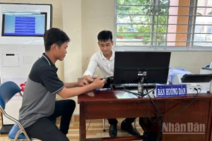 Cán bộ Trung tâm Phục vụ hành chính công xã Mỹ Lợi hướng dẫn người dân thao tác nộp hồ sơ trực tuyến. 