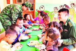 Thiếu tá Cầm Bá Thành (bên phải ảnh) cùng với đồng đội thực hiện “Bữa sáng cho em” tại điểm Trường mầm non Buốc Pát.
