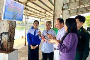 Ngư dân quét mã QR “Bảng mã QR phổ biến, tuyên truyền các quy định về phòng, chống IUU” tại cảng cá Tiên Châu.