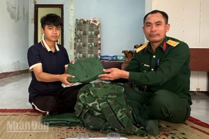 Thanh niên Vi Hồng Minh nhận quân phục mới từ cán bộ Ban chỉ huy Quân sự xã Ia Rvê.