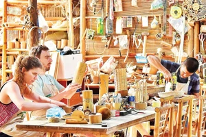 Du khách tự làm sản phẩm lưu niệm bằng tre tại một cơ sở thủ công mỹ nghệ ở Đà Nẵng. (Ảnh: MỸ HÀ)