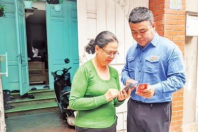 Đoàn viên thanh niên phường Thụy Khuê (Tây Hồ) hướng dẫn sử dụng ứng dụng “Sổ tay đảng viên điện tử Thành ủy Hà Nội”. (Ảnh VIẾT TUẤN)