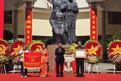 Đồng chí Dương Văn Trang trao tặng cờ và danh hiệu Anh hùng Lực lượng vũ trang nhân dân cho đại diện Tập thể chiến sĩ cách mạng bị địch bắt tù đày tại Ngục Kon Tum. 