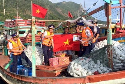 Cán bộ Bộ Tư lệnh Cảnh sát biển trao cờ Tổ quốc và quà tặng ngư dân tại cảng Bến Đầm, huyện Côn đảo, tỉnh Bà Rịa-Vũng Tàu. (Ảnh: nhandan.vn) 