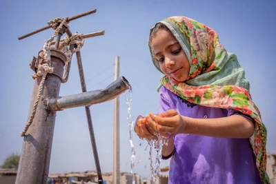 Một cô bé đang uống nước từ máy bơm tay tại Pakistan. Nguồn: UN