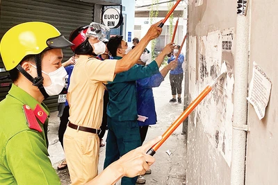 Công an, cảnh sát giao thông và các lực lượng phối hợp bóc gỡ các mẫu quảng cáo, tờ rơi dán sai nơi quy định. (Ảnh CTV) 