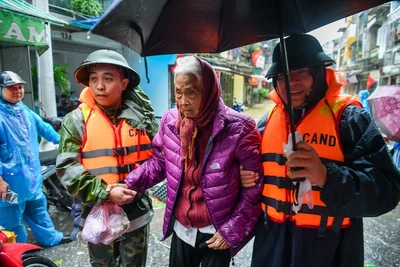 Lực lượng công an hỗ trợ người dân các phường ngoài đê sông Hồng đi sơ tán khi nước lũ dâng cao. (Ảnh: THẾ ĐẠI)