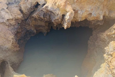 Nước ngầm đùn ra theo hàm ếch dưới đáy hố sụt. (Ảnh: TUẤN SƠN)