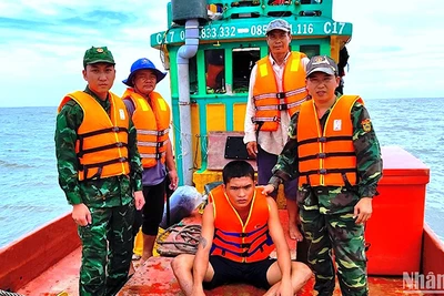 Nạn nhân Minh (ngồi) bị trôi dạt trên biển được Bộ đội Biên phòng Cà Mau cứu vớt đưa vào bờ an toàn. 