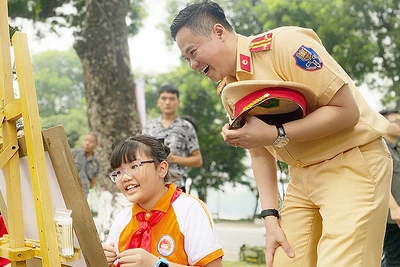 Cán bộ cảnh sát giao thông hào hứng với tác phẩm của thí sinh tại cuộc thi vẽ tranh "Thiếu nhi Thủ đô với an toàn giao thông" trong khuôn khổ Ngày hội.