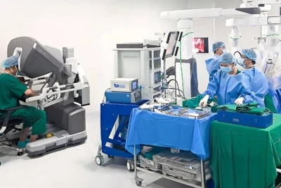 Phó Giáo sư, Tiến sĩ Vũ Lê Chuyên (trái) đang ngồi ở buồng điều khiển robot Da Vinci Xi để phẫu thuật cho người bệnh.