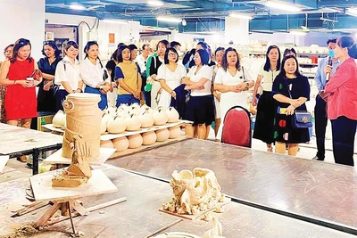 Chủ tịch Hiệp hội Thủ công mỹ nghệ và làng nghề Hà Nội Hà Thị Vinh giới thiệu với khách tham quan về gốm Bát Tràng (huyện Gia Lâm).