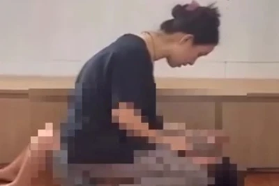 Người phụ nữ ngồi lên bụng cháu bé mặc cho bé khóc thét, sợ hãi (Ảnh cắt từ clip)