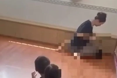 Người phụ nữ ngồi trên bụng cháu bé (Ảnh cắt từ clip) 