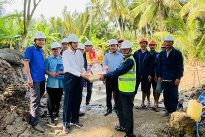 Thành viên Hội đồng thành viên EVNSPC Lê Xuân Hải (áo trắng) tặng quà động viên lực lượng lao động thi công dự án trên địa bàn tỉnh Bến Tre ngày 26 Tết.