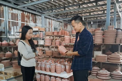 Nghệ nhân Nguyễn Mạnh Hòa (phải) giới thiệu những sản phẩm mới với du khách. 