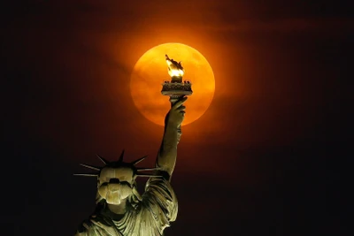 Siêu trăng mọc qua màn sương mù phía sau Tượng Nữ thần Tự do ở thành phố New York, Mỹ. (Ảnh: Getty Images)