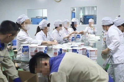 Công nhân đóng hộp thành phẩm tại cơ sở sản xuất sữa bột giả quy mô lớn vừa bị Công an thành phố Hà Nội triệt phá. (Ảnh: Báo Công an nhân dân)