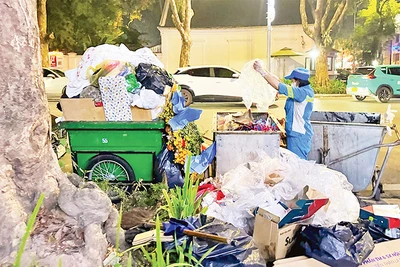 Công nhân Công ty Môi trường đô thị Hà Nội thu gom rác thải trên phố Bà Triệu. (Ảnh LÊ MINH)