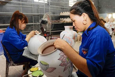 Vẽ hoa văn lên sản phẩm tại làng gốm Bát Tràng, Hà Nội. (Ảnh TUỆ NGHI)