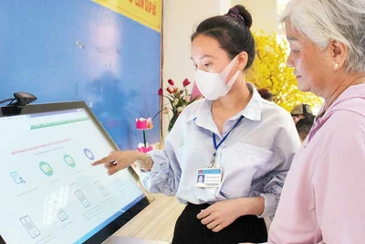 Cán bộ phường Bến Nghé, Quận 1 hướng dẫn người dân thực hiện đăng ký hồ sơ trực tuyến. (Ảnh: THẾ ANH)