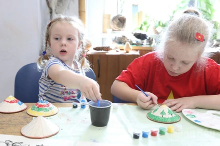 Các “nghệ nhân nhí” say sưa tô vẽ những chiếc nón lá Việt Nam.