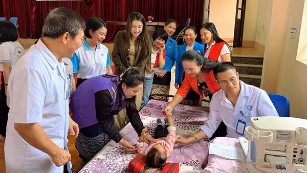 Phụ nữ cùng bác sĩ chăm sóc, khám bệnh cho trẻ em Lào.