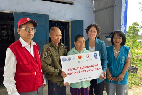 Đại diện Chương trình Phát triển Liên hợp quốc (UNDP) trao tiền hỗ trợ cho gia đình bị ảnh hưởng bởi bão lũ.