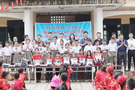 Đại diện Văn phòng Báo Nhân Dân tại Hà Tĩnh cùng lãnh đạo cấp uỷ, chính quyền địa phương và nhà tài trợ trao tặng gần 500 áo đồng phục cho học sinh Trường tiểu học Hương Liên.