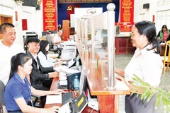 Chủ tịch Ủy ban nhân dân xã Tà Năng Nguyễn Vũ Linh Sang (bìa trái) hướng dẫn cán bộ Trung tâm phục vụ hành chính công xã ứng dụng AI phục vụ người dân làm thủ tục hành chính.