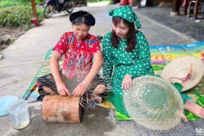 Bà Hoàng Thị Huệ (bên trái) trò chuyện và hướng dẫn khách làm nón.