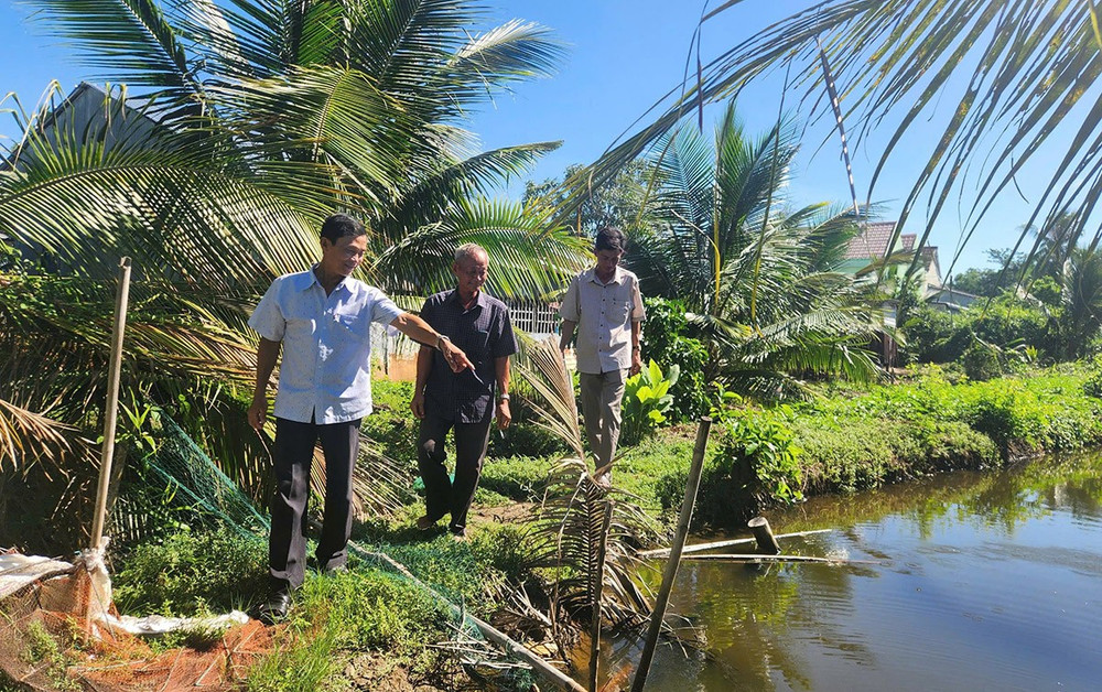 Ông Năm Dậu (giữa) cùng cán bộ địa phương đến tận nơi tìm hiểu, giải quyết ổn thỏa mâu thuẫn trong tranh chấp đất của hai hộ dân.