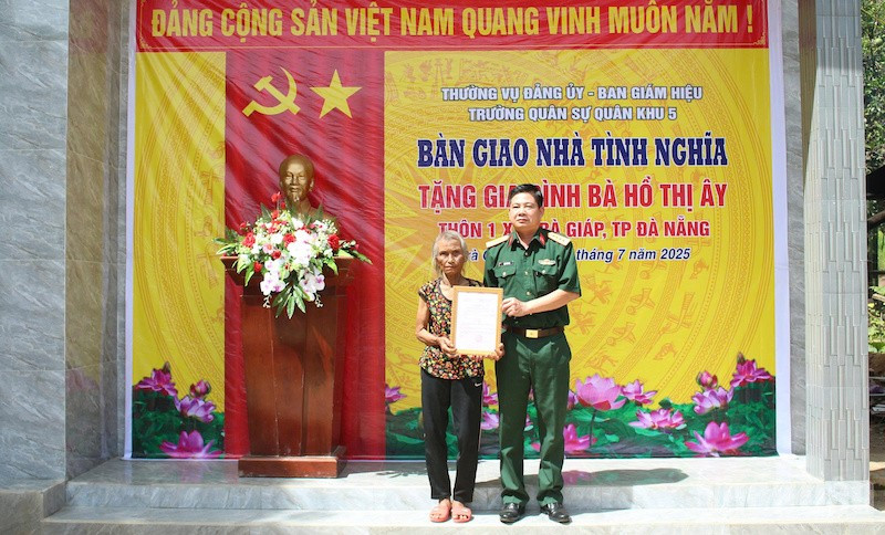 Đại tá Đặng Văn Trụ - Chính ủy Nhà trường trao quyết định tặng nhà bà Hồ Thị Ây. (Ảnh: ĐÌNH TĂNG) ndo_br_qku5.jpg