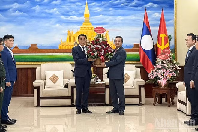 Đại sứ Nguyễn Minh Tâm trao lẵng hoa tươi thắm tới đồng chí Bounleua Phandanouvong, Trưởng Ban Đối ngoại Trung ương Đảng Nhân dân Cách mạng Lào. (Ảnh: Cộng tác viên)