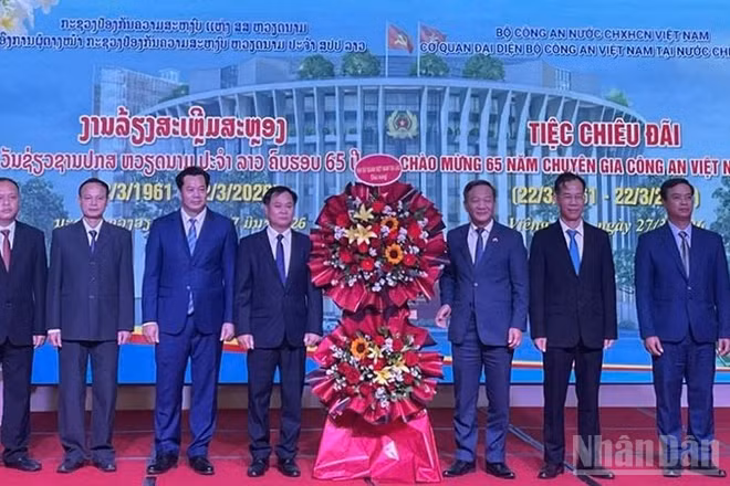 Đại sứ Nguyễn Minh Tâm (thứ 3 từ phải qua) tặng hoa chúc mừng đội ngũ Chuyên gia Công an Việt Nam tại Lào. (Ảnh: DUY TOÀN)